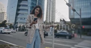 微笑卷曲的女人在中心城市街道和使用她的电话。 在佳能相机上拍摄12位颜色深度。